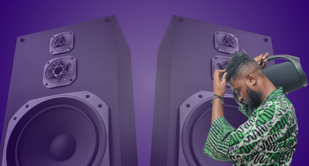 Two big speakers in the background and person carrying a speaker